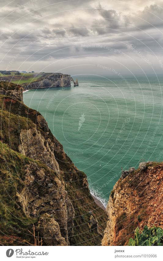 Étretat Natur Landschaft Himmel Wolken Horizont schlechtes Wetter Felsen Berge u. Gebirge Wellen Küste Meer groß hoch braun grau grün Tourismus Umwelt Bogen