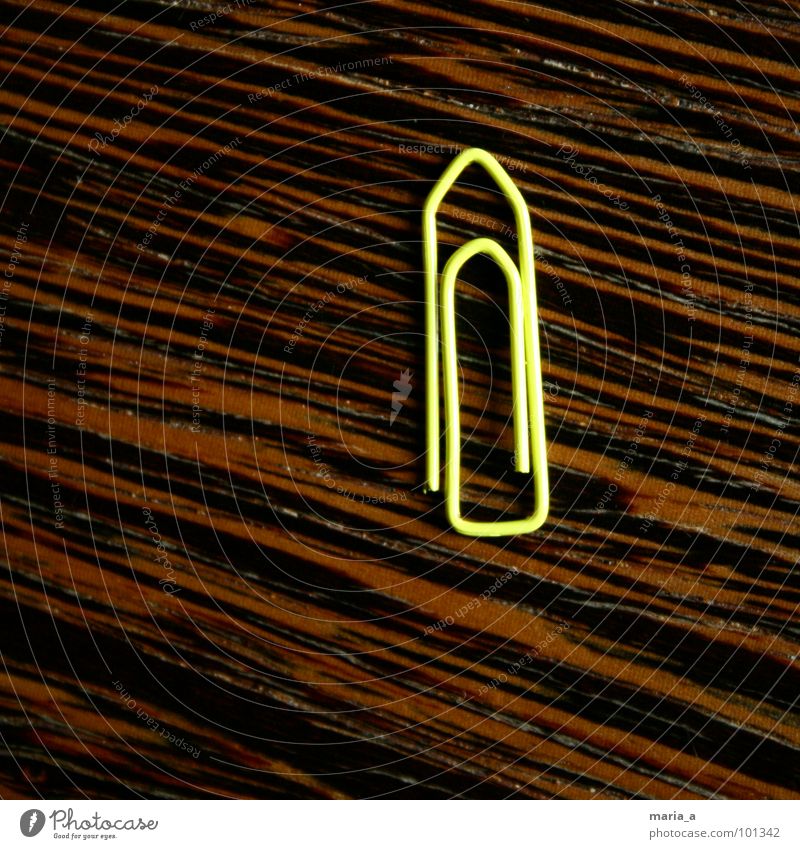 gelb - eine von 1000 Büroklammern Zusammenhalt Draht beweglich Biegung Holz dunkel Einsamkeit Quadrat holzmaerung Maserung hell einzelnd einzige