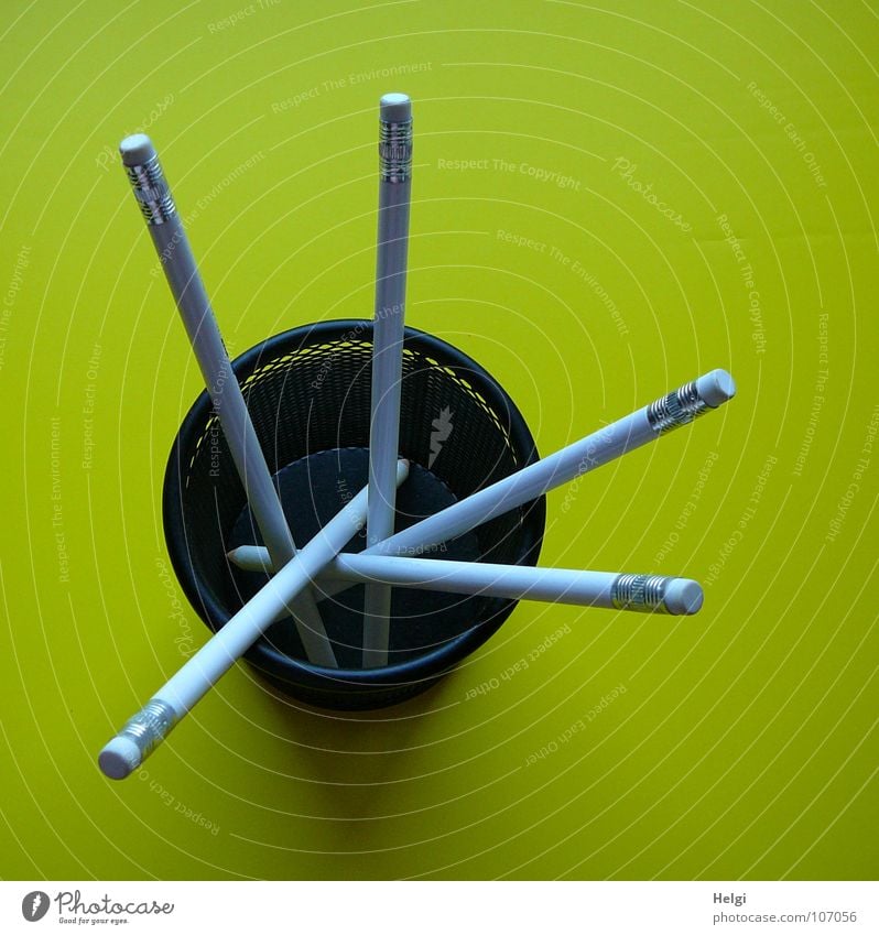 Stifte mit Radiergummi stehen in einer runten Box auf gelbem Hintergrund Schreibstift Bleistift Becher Draht lang dünn vertikal durcheinander nebeneinander