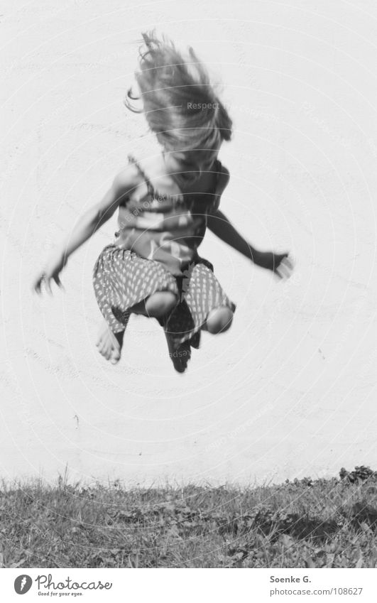 Jump Kind Mädchen springen Mauer Wiese Spielen träumen Hippie toben Freude Schwarzweißfoto Haare & Frisuren hoch Schatten kleines kind tagträumen