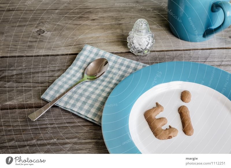 Die Buchstaben Ei auf einem Teller mit Serviette und Teelöffel, ein Salzstreuer und einer Tasse auf einem rustikalen Holztisch Lebensmittel Ernährung Frühstück