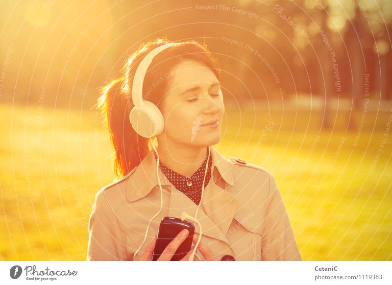 Frau, die im Sonnenlicht Musik hört. Lifestyle Freude MP3-Player feminin Junge Frau Jugendliche Erwachsene 18-30 Jahre Natur Park Fröhlichkeit selbstbewußt