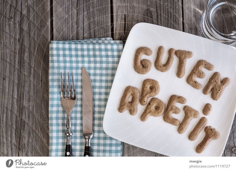 Die Buchstaben Guten Appetit auf einem Teller mit Serviette, Messer, Gabel und einem Wasserglas Lebensmittel Ernährung Frühstück Mittagessen Abendessen Büffet