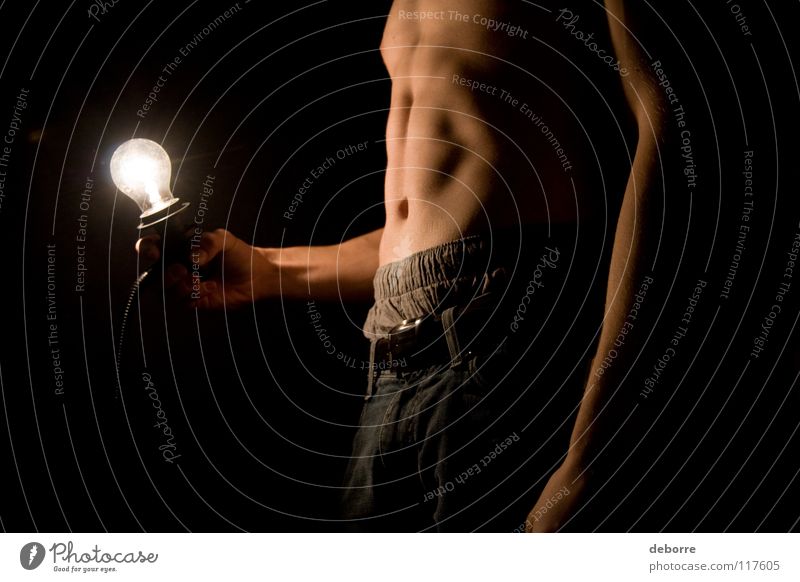 Junger Mann posiert oben ohne mit Glühbirne im Dunkeln. Nahaufnahme Kerl Licht nackt schwarz Arme schlecht Magen Beine Bauch Kumpel Typ Haut Jeanshose Knolle