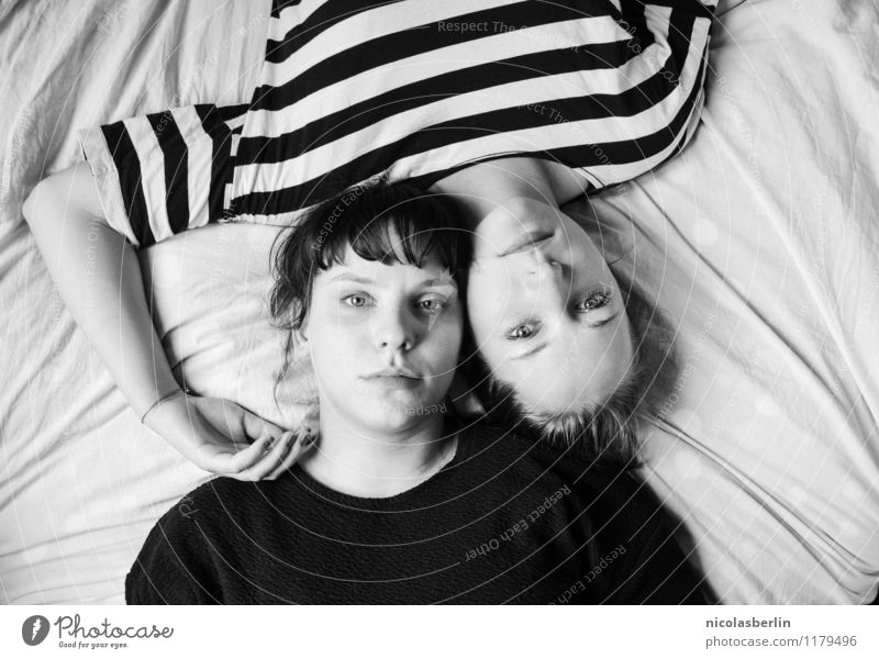 Zwei junge Frauen liegen lässig auf Bett mit Köpfen zusammen und gucken in die Kamera Paar schön feminin Liebe Freundschaft Junge Frau harmonisch Wohlgefühl