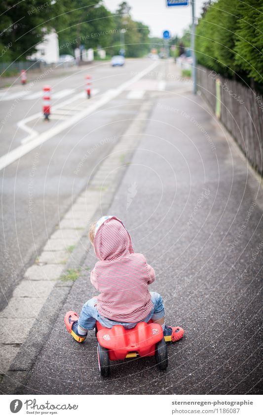Straßenverkehr Bobbycar Kind Kindheitserinnerung Kleinkind PKW Bürgersteig Fußweg fahren Spielen rot Spielzeug Verkehrsleitkegel Pylon Kapuze