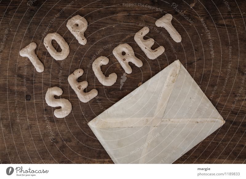 Die Buchstaben TOP SECRET mit einem Briefumschlag auf einem rustikalen Holztisch Prüfung & Examen Büroarbeit Arbeitsplatz Wirtschaft Industrie