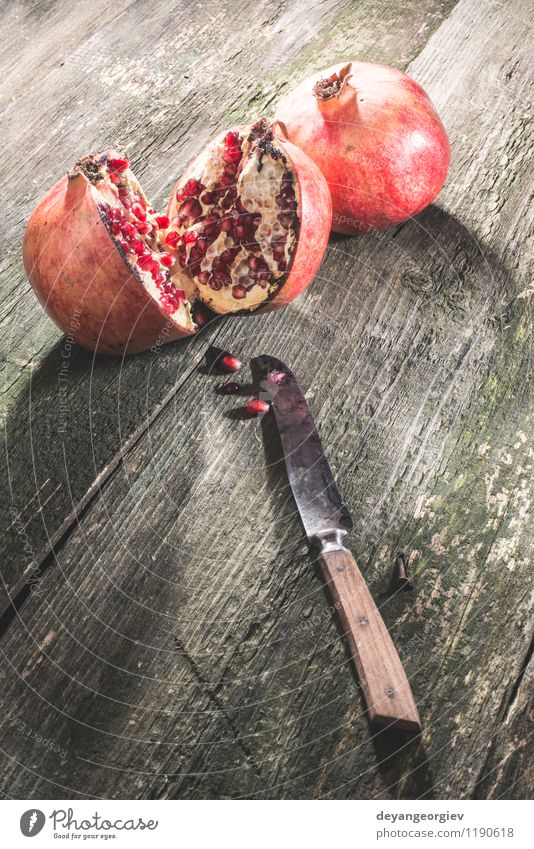 Granatapfel auf Holztisch Frucht Dessert Essen Vegetarische Ernährung Diät Saft Tisch alt dunkel frisch retro saftig rot Farbe hölzern Messer altehrwürdig