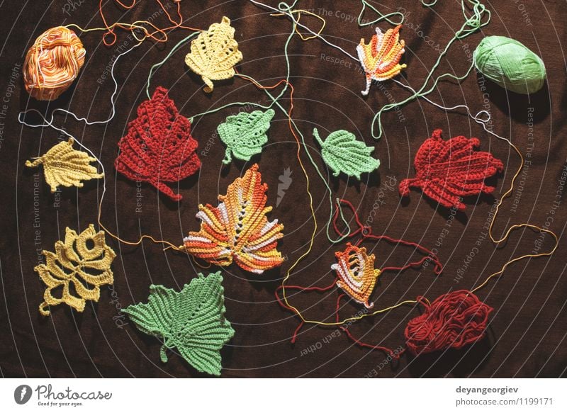Gestrickte Herbstblätter auf braunem Textil Glück schön stricken Erntedankfest Natur Blatt Pullover Hut gelb rot fallen gestrickt Hintergrund Jahreszeiten Ahorn