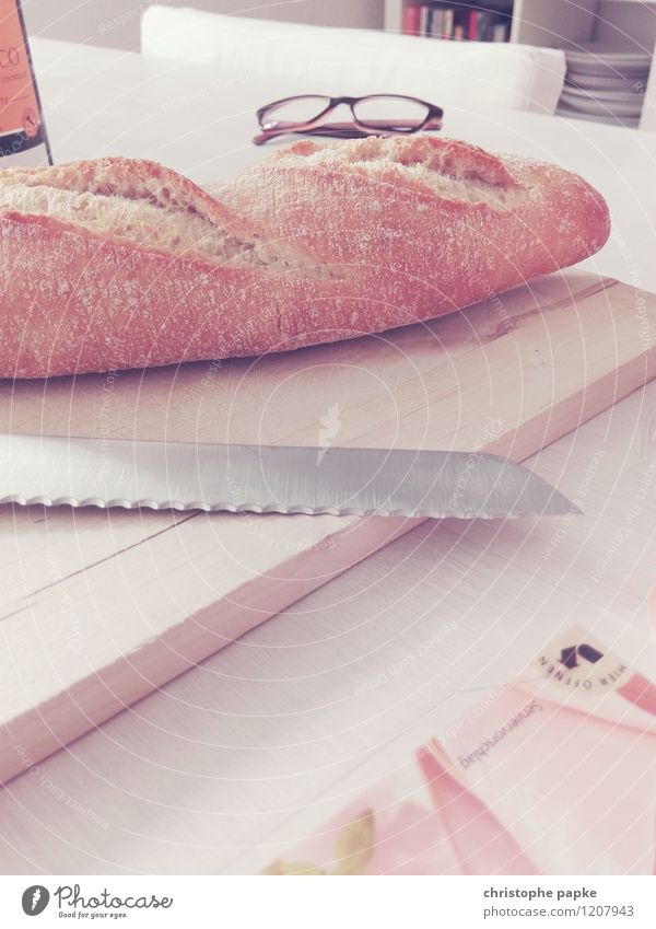 Baguette mit Messer auf Brett auf Tisch Lebensmittel Brot Ernährung Frühstück Häusliches Leben brotmesser Brille Holzbrett Farbfoto Gedeckte Farben