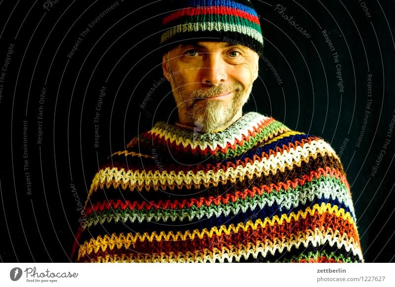 Mann mit gestrickter Wollmütze und gehäkelter Wolldecke Mensch Erwachsene Senior Porträt Gesicht mehrfarbig Muster Streifen Umhang Pullover Mütze Wärme Bart