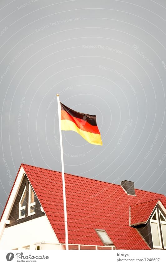 Deutschlandfahne weht über einem deutschen Neubau, Haus Nationalflagge Gewitterwolken Deutsche Flagge Patriotismus Einfamilienhaus authentisch Originalität