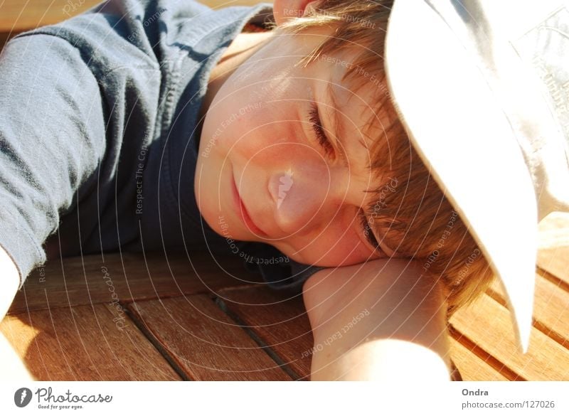 Schlafkappe Junge maskulin Kind schlafen lümmeln Baseballmütze blenden Sommer Holz Tisch Wasserfahrzeug Mensch liegen Müdigkeit Erholung grinsen Schönes Wetter