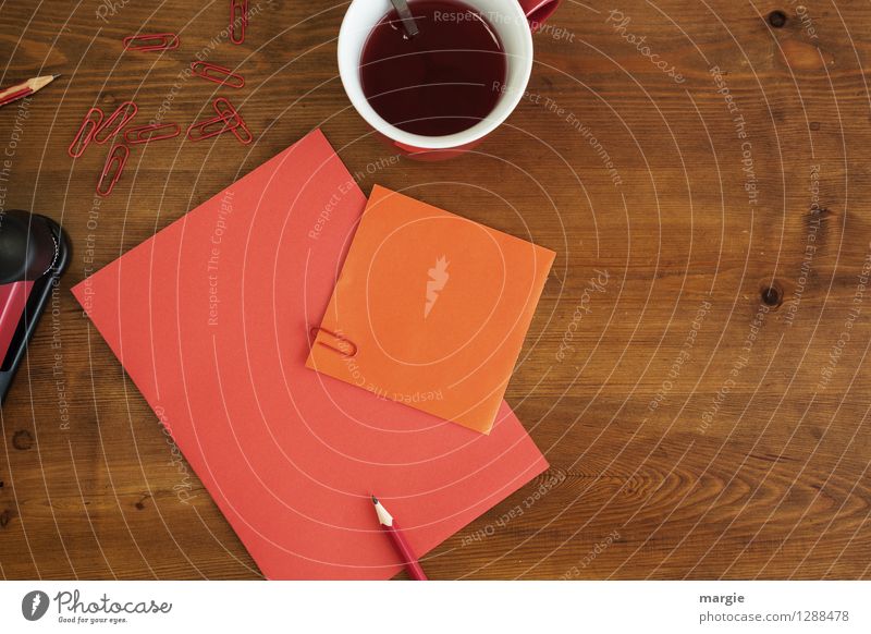 Rot oranges Büro: Zettel mit Bleistift, Büroklammern und eine Tasse roter Tee Heißgetränk Kaffee Löffel Schreibtisch Tisch Schule lernen Büroarbeit Business