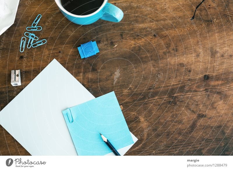 Blaues Büro: Zettel mit Bleistift, Spitzer, Büroklammern, Radiergummi und eine Kaffeetasse Getränk Heißgetränk Tasse Schreibtisch Tisch Schule lernen Schüler