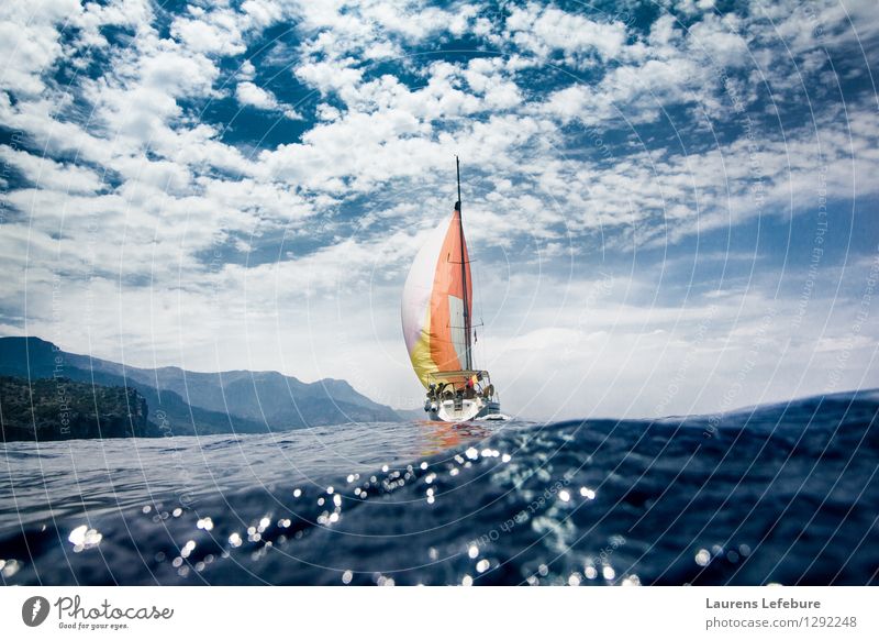 Segelboot mit buntem Segel. Geschossen aus dem Wasser. Erde Himmel Wolken Sommer Schönes Wetter Meer Mittelmeer Kreativität Segeln Segelschiff Wellen Farbe