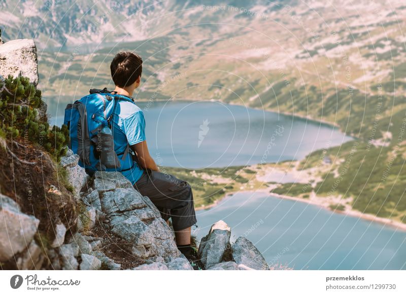 Jugendlicher, der auf Felsen stillsteht und die Berge betrachtet Lifestyle schön Ferien & Urlaub & Reisen Ausflug Abenteuer Freiheit Sommer Berge u. Gebirge