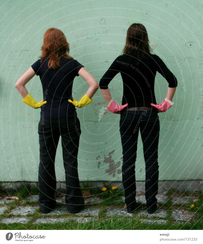 Zwei Frauen von hinten mit Gummihandschuhen Handschuhe rosa gelb knallig Rauschmittel türkis Wand beschrieben dreckig Reinigen edel skurril seltsam Karneval