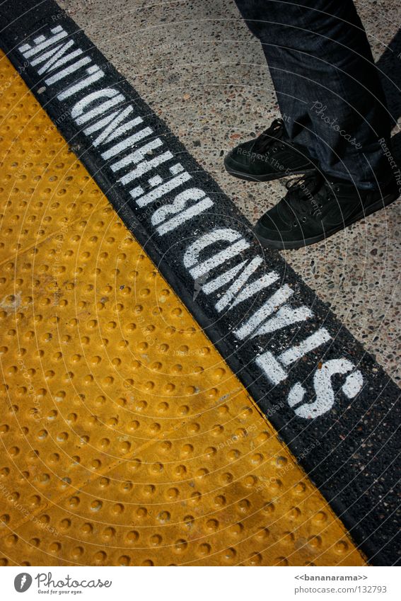 STAND BEHIND LINE stoppen Straßenbahn Verbote gelb Eisenbahn schwarz stehen Busbahnhof Schuhe Abtrennung Langeweile Buchstaben Schriftzeichen Hinweisschild