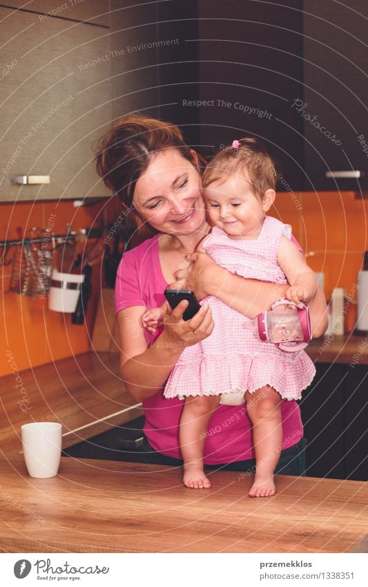 Frau, die ihren kleinen Tochtervideoanruf mit Großmutter zeigt Lifestyle Freude Glück Küche Baby Kleinkind Mädchen Erwachsene Eltern Mutter