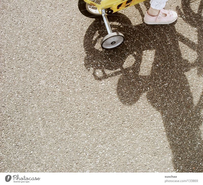 99 .. Asphalt Kind Kleinkind Mädchen klein gelb fahren Verkehrswege Freude Straße fahrad stützräder Fuß Fahrrad Außenaufnahme