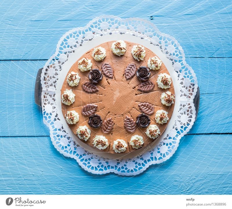 Schokosahnetorte auf blauem Holz mit Tortenspitze Kuchen Dessert Schokolade Schokoladen-Sahne-Torte Schaumgebäck Backwaren Biskuit Holztisch rustikal