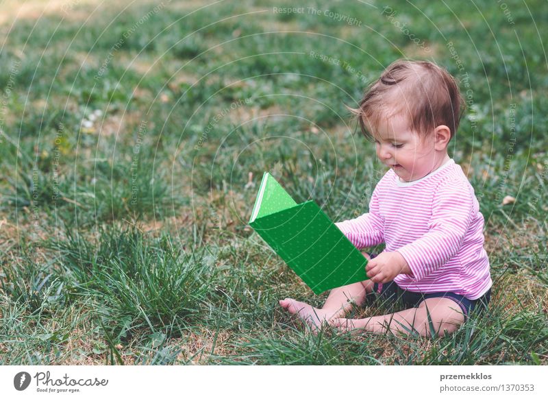Kleines Baby, das ein Buch mit Bildern überwacht Lifestyle Freude Glück schön Kind Mensch Kleinkind Mädchen Kindheit 1 0-12 Monate Gras beobachten Blick sitzen