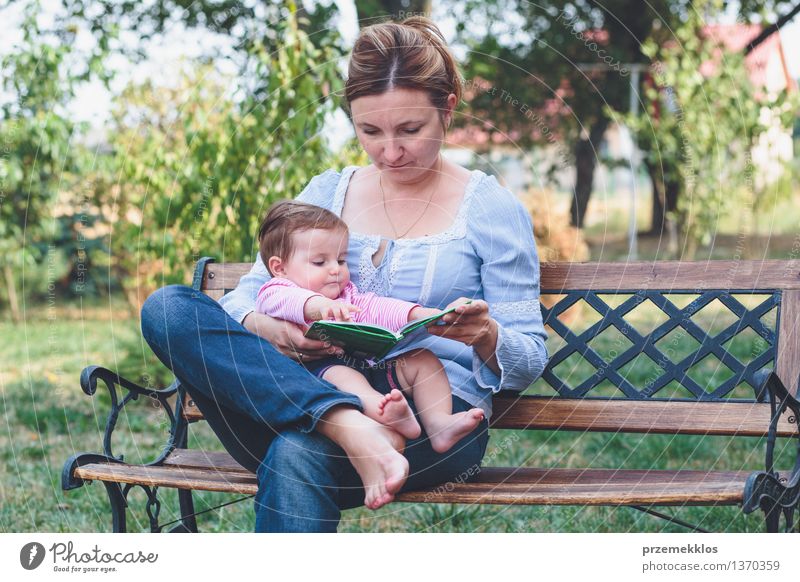 Mutter, die ein Buch ihre kleine Tochter liest Lifestyle Freude Glück schön Leben lesen Garten Kind Baby Kleinkind Mädchen Frau Erwachsene Eltern