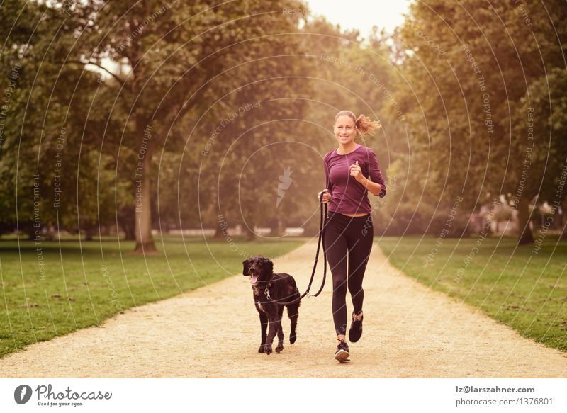 Gesunde Frau, die im Park mit ihrem Hund rüttelt Lifestyle Erholung Sommer Sport Joggen Erwachsene Freundschaft Tier Wege & Pfade Haustier Fitness Lächeln