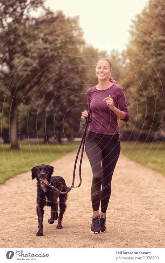 Gesunde Frau, die im Park mit ihrem Hund rüttelt Lifestyle Erholung Sommer Sport Joggen Erwachsene Freundschaft Tier Wege & Pfade Haustier Fitness Lächeln