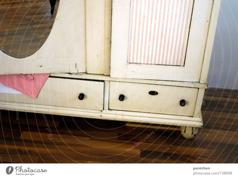 Nachhaltigkeit. Ein Vintage KleiderSchrank in rosa und weiß steht auf laminatboden. Antiquität. Möbel. Vergangenheit schön Häusliches Leben Wohnung einrichten