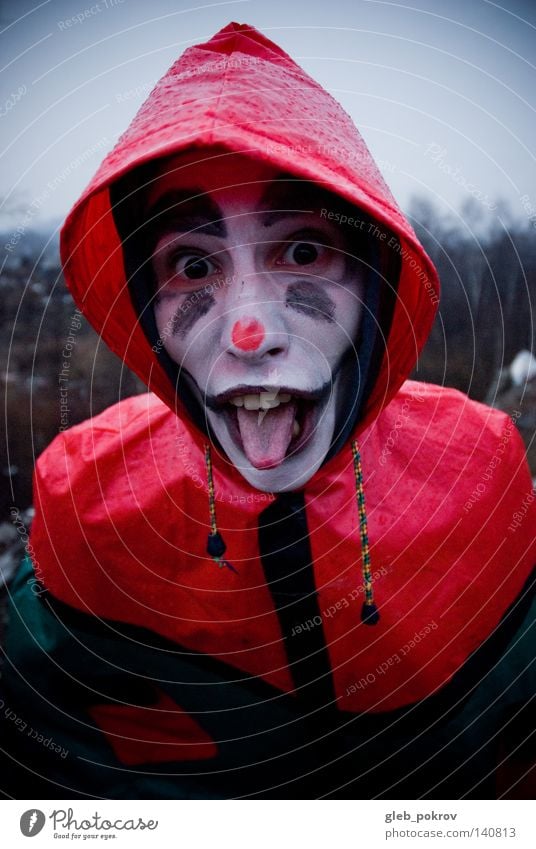 Verrückter Clown. Porträt Mann Zähne Straße Müll Nase Bekleidung Sibirien Luft Kapuze Kopf Hut Freude grimmig Männer gedacht Regen rot dunkel Kapuzenpulli