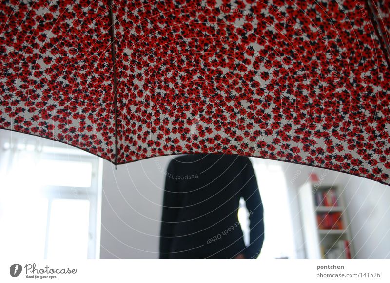 Kopflos. Mann steht in einem hellen zimmer. Sein Kopf wird von einem Regenschirm verdeckt. Verstecken Marienkäfer Raum weiß Licht Regal verstecken Wohnung rot