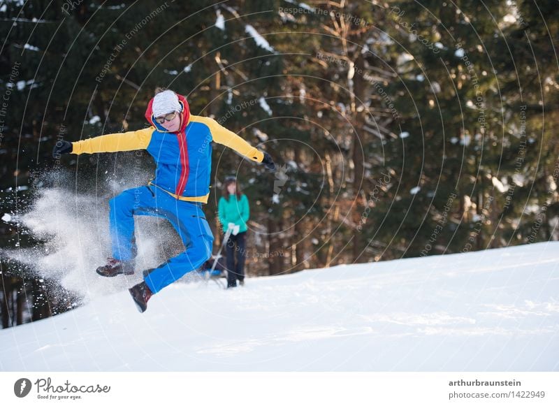 Junger Mann springt in die Luft und hat Spaß im Schnee Freude Tourismus Ausflug Winter Winterurlaub wandern Wintersport Mensch maskulin feminin Junge Frau