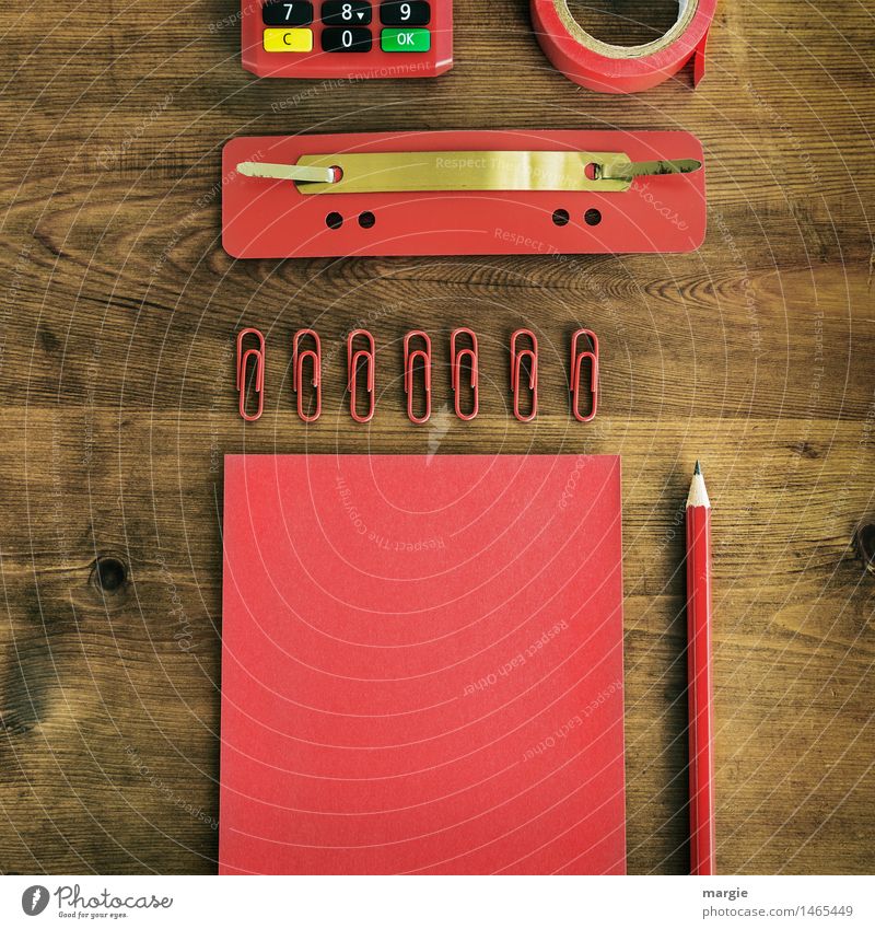 Im Q- Format: rote Schreib- Utensilien, Papier, Zettel, Bleistift, Büroklammern, Heftlasche, Klebeband, Rechner auf einen Holz- Schreibtisch Berufsausbildung