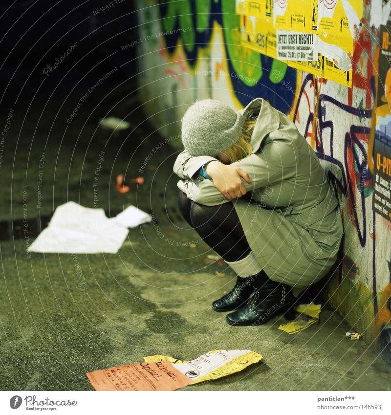Sara Jane Frau Trauer sitzen hocken Mantel Strumpfhose Mütze Wollmütze Graffiti Aufschrift Unterführung nass kalt Wand mehrfarbig Verzweiflung Liebeskummer