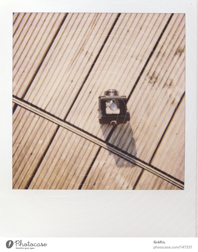 Lubitel Polaroid Geschwindigkeit teuer Lomografie Fotokamera Fotografieren Balkon Holzfußboden Bodenbelag Holzbrett Sommer Schatten minimalistisch Furche quer