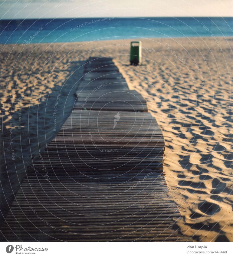 einfach geradeaus Strand Meer Sand Schatten Müllbehälter blau Bürgersteig Schiffsplanken Holz Horizont leer Fußspur Physik Abend Fuerteventura Unschärfe