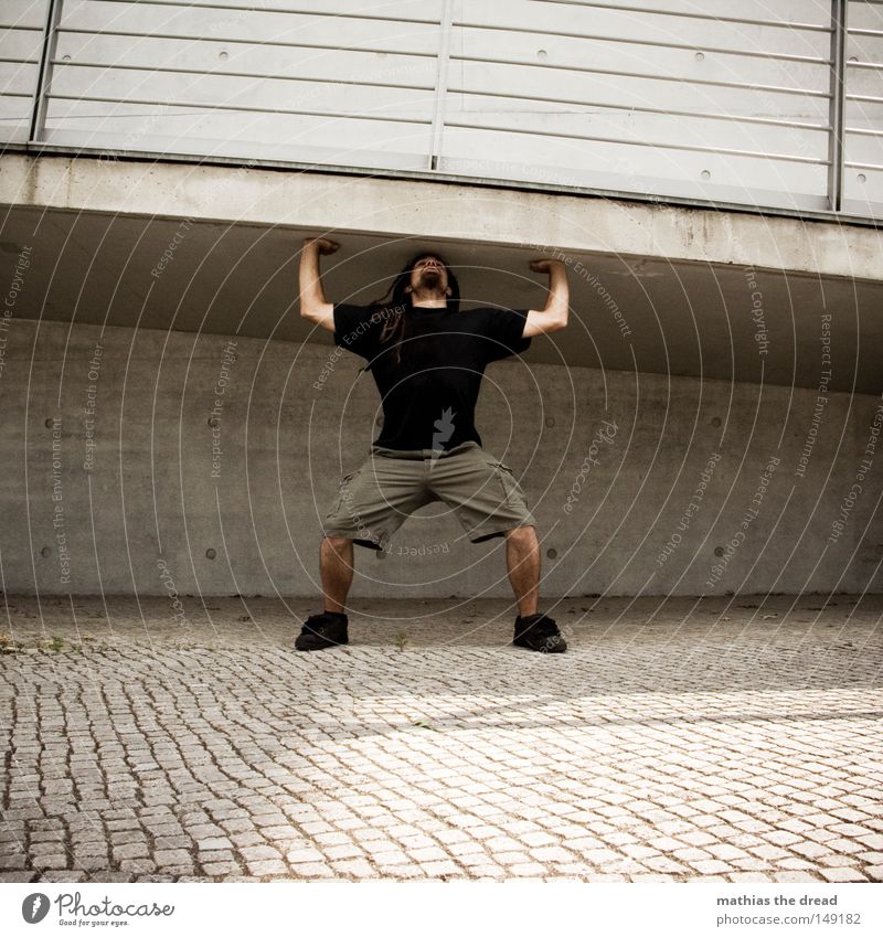 BLN 08 | I AM STRONG Gewichtheben Krafttraining Junger Mann Rastalocken Ganzkörperaufnahme Architektur Fußgängerbrücke Beton Betonbauweise anstrengen Witz