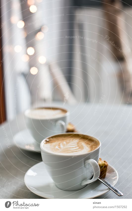 Cappuccinos Kaffee Tasse Milch milchschaum latte art latteart Löffel Keks Licht blur genießen Koffein Tisch grau Beton Gegenlicht braun weiß Feder Frühstück