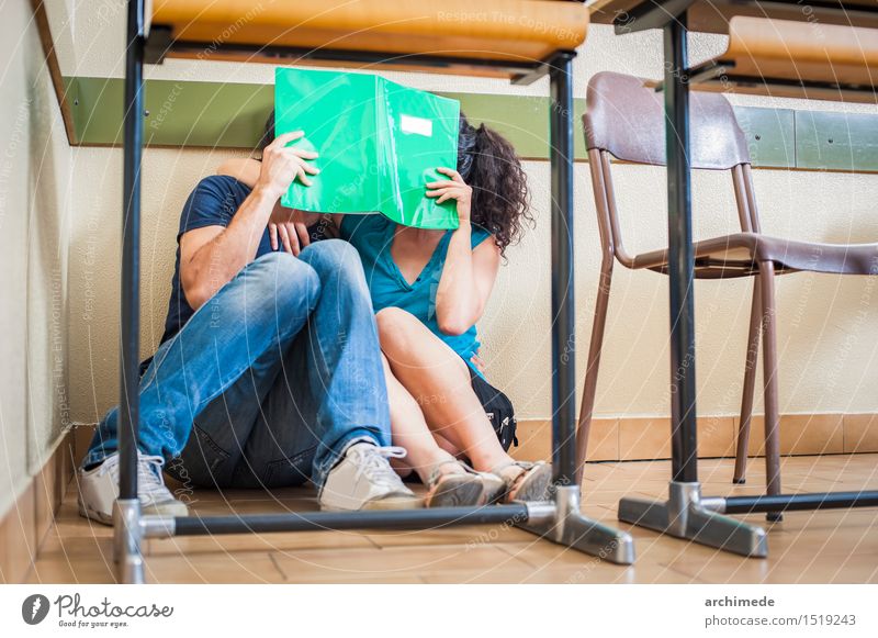 Paarstudenten, die im Klassenzimmer küssen Lifestyle Freude Glück Tisch Schule Klassenraum Frau Erwachsene Mann Freundschaft Jugendliche Buch Küssen Liebe