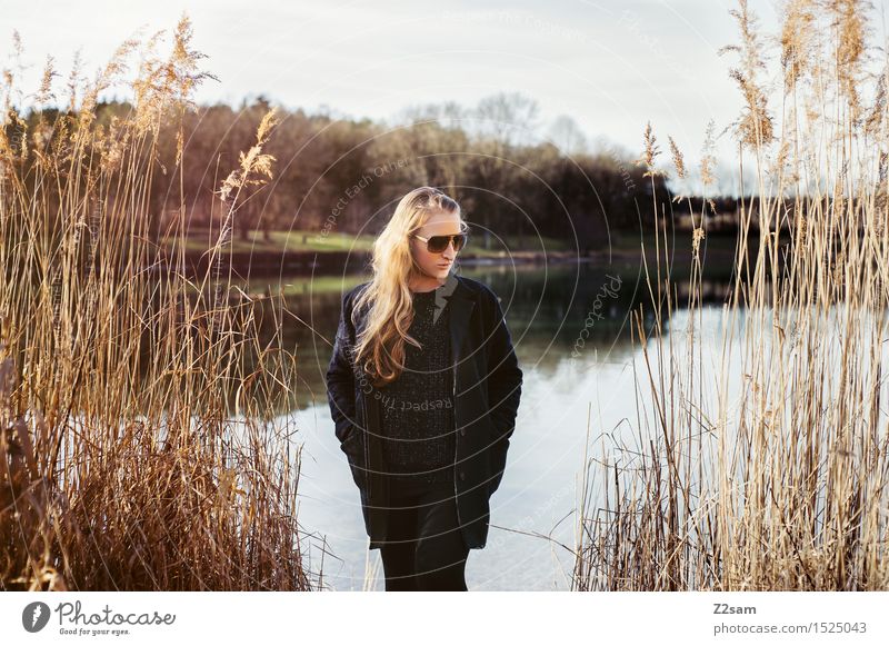 Ein Tag am See Lifestyle elegant Stil Sonne Junge Frau Jugendliche 18-30 Jahre Erwachsene Landschaft Frühling Sträucher Seeufer Mode Mantel Sonnenbrille brünett