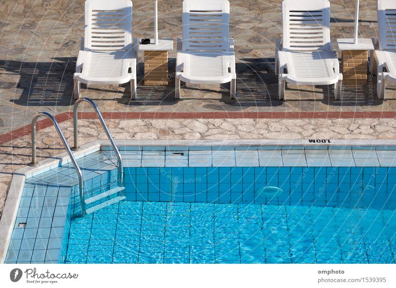 Sauberer blauer Swimmingpool mit klarem Wasser und Sonnenliegen drum herum an einem heißen Sommermorgen. Lifestyle schön Erholung Spa Schwimmbad