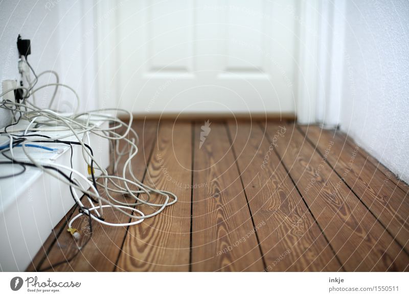 Kabelsalat im Flur Häusliches Leben Holzfußboden Holztür Telekommunikation Menschenleer chaotisch unordentlich durcheinander Farbfoto Innenaufnahme Nahaufnahme