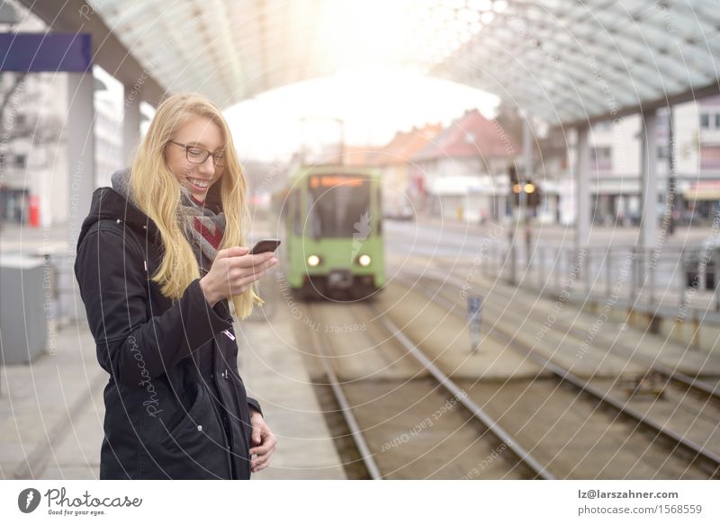 Junge Frau mit Handy an der Bahnstation Glück Ferien & Urlaub & Reisen Winter Telefon Erwachsene 1 Mensch 18-30 Jahre Jugendliche Verkehr Eisenbahn blond