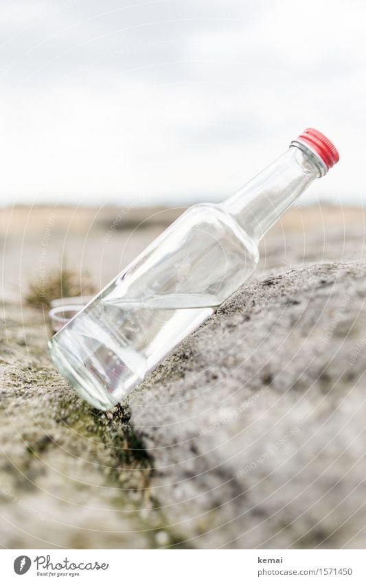 Die Flasche ist halb voll Getränk Trinkwasser Alkohol Spirituosen Glasflasche Schnapsflasche Felsen Stein stehen authentisch hell rot durchsichtig Neigung