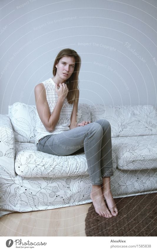 Erfahre mehr darüber elegant Sofa Raum Junge Frau Jugendliche Beine 18-30 Jahre Erwachsene Jeanshose Top Barfuß brünett langhaarig Blick sitzen ästhetisch