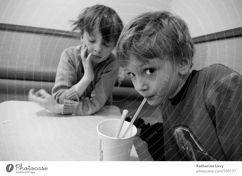 Fast Food Schwarzweißfoto Innenaufnahme Zentralperspektive Weitwinkel Blick in die Kamera Getränk trinken Becher Trinkhalm Kind Mensch Junge Kindheit 2