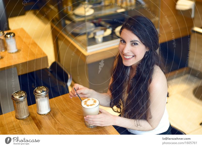 Lächelnde Brunettefrau, die in einem trinkenden Kaffee der Bar sitzt Latte Macchiato Lifestyle schön Erholung Tisch Frau Erwachsene 1 Mensch 18-30 Jahre
