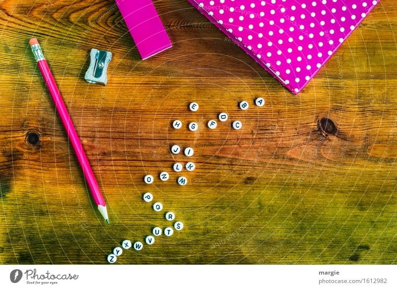 Alle Buchstaben des Alphabet, ein Heft, ein Stift und ein Radiergummi in der Farbe pink auf einem Holztisch Schule lernen Arbeit & Erwerbstätigkeit Beruf
